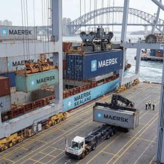 Container being transferred from a cargo ship to a terminal truck.